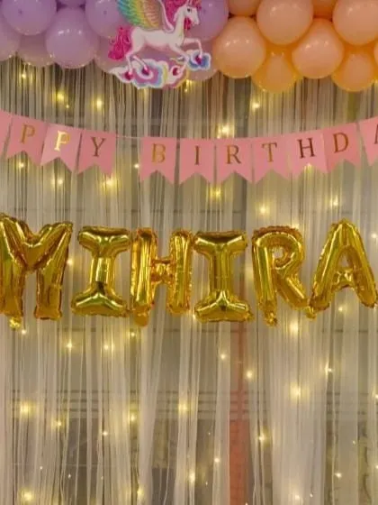 I brought a magical rainbow and unicorn theme to life for Mihira's birthday. This setup features a pastel rainbow balloon arch framing a shimmering backdrop with fairy lights. The gold foil letter balloons spelling out the name add a beautiful centerpiece for photos.