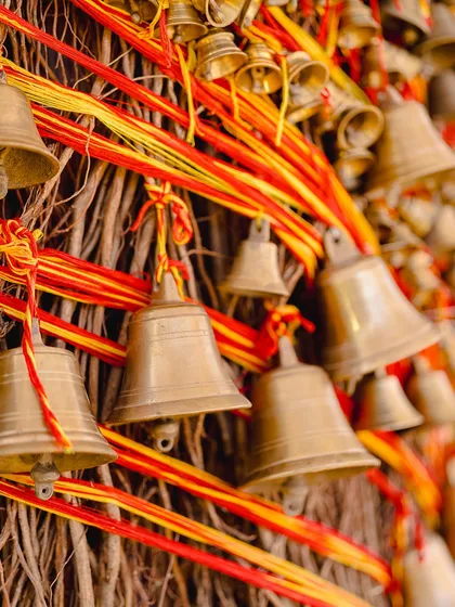 A detail of the tree trunk, made from natural twigs and adorned with hundreds of brass temple bells tied with sacred red and yellow threads.