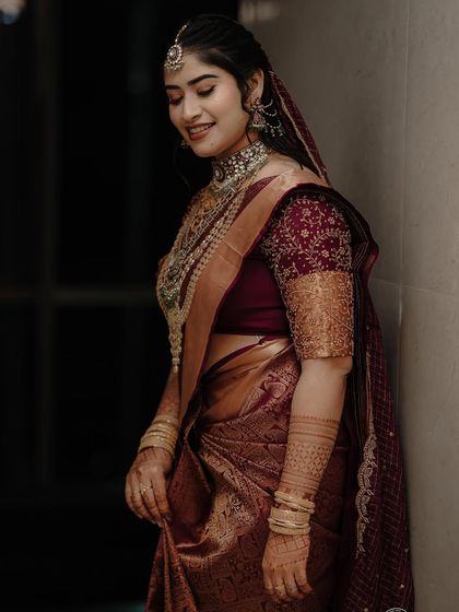 This bride's deep maroon saree for her reception is the definition of elegance. The draping style is sophisticated, with a focus on a clean pallu and perfectly falling pleats.