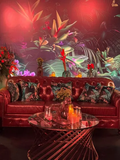 The allure of a mood-lit night. This lounge area, with its rich leather sofa and jungle-themed backdrop, is the perfect place to relax and soak in the party atmosphere.