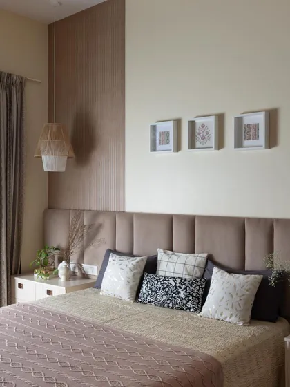 Texture and tranquility define this space. A soft, upholstered headboard is framed by a textured accent wall, creating a subtle yet sophisticated look. The mix of cushions adds another layer of comfort.