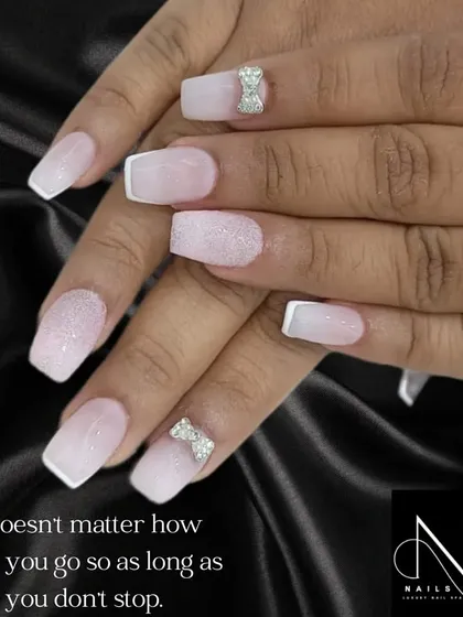 A sweet and elegant design perfect for a wedding or engagement. This set features a soft pink and white ombre base on square nails, accented with sugar glitter and delicate silver rhinestone bows.