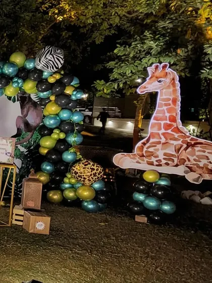 The other side of the safari party backdrop, featuring a large giraffe cutout resting on a cluster of green and black balloons. This creates a balanced and symmetrical look for the main photo area.