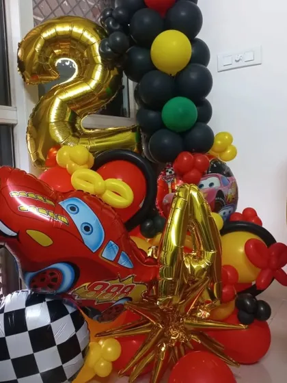 A balloon bouquet with a car theme, featuring a large number '2' foil balloon and a Lightning McQueen car balloon.