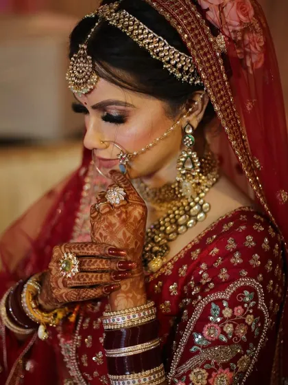 A detailed shot of the bride's hands, adorned with henna and beautiful rings, as she adjusts her nath.