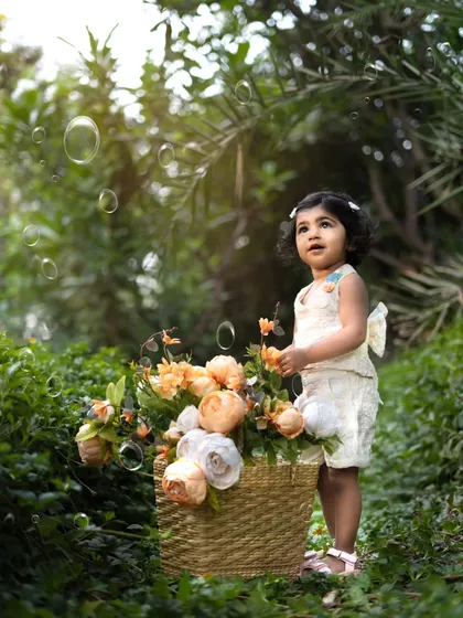 Bubbles and flowers in the garden. This toddler looks up in wonder, creating a dreamy and enchanting outdoor portrait.