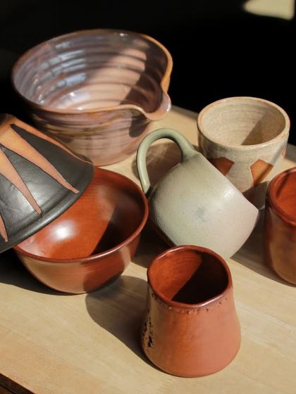 A dynamic group of student works, including a large mixing bowl and pieces with bold, graphic patterns applied with underglaze.