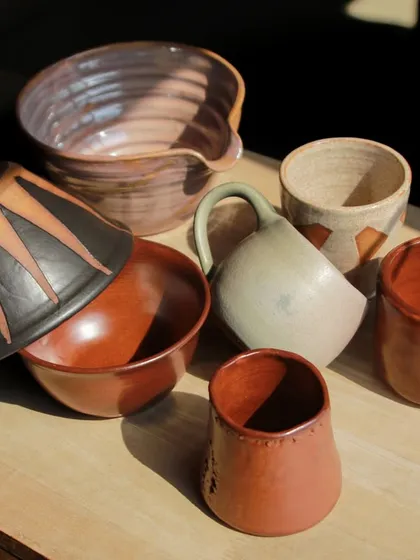 A dynamic group of student works, including a large mixing bowl and pieces with bold, graphic patterns applied with underglaze.