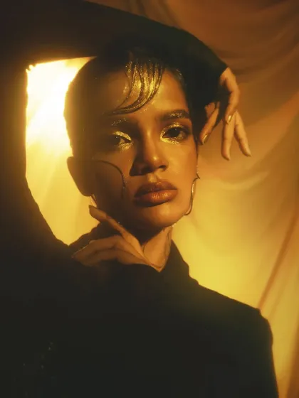 A striking close-up where the light catches the gold glitter on the eyes and the sleek, graphic hair details.