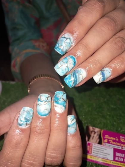 A beautiful blue and white marble design on square nails, accented with delicate gold lines.