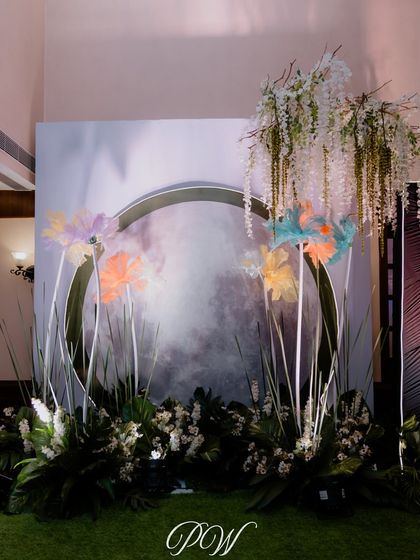 A whimsical photo backdrop for a Sangeet. The design features giant abstract flowers against a painted canvas, creating a unique and artistic setting.
