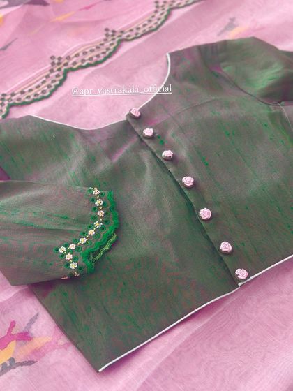 A green blouse with delicate floral embroidery on the cuffs and button placket.