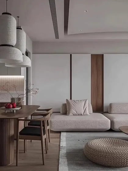 A view of an open-plan living and dining area designed with a Japanese-inspired minimalist aesthetic. The low-profile sofa, natural wood dining set, and paper lantern-style pendant lights create a serene and harmonious environment.