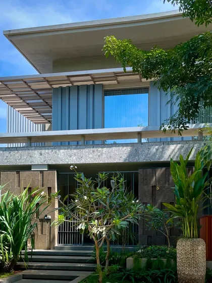 The 'STILL HOME' in Tiruppur, where a monochrome grey palette unifies diverse architectural forms. The design uses tropical modern elements and lush greenery to create a state of tranquility and stillness.