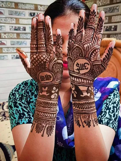 Another view of the "Aai-Baba" mehandi, showing the intricate patterns that surround the meaningful text.