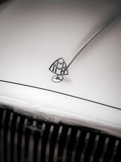 A black and white detail shot of the iconic Maybach hood ornament. This minimalist and elegant style of photography is ideal for highlighting the heritage and luxury associated with high-end automotive brands.