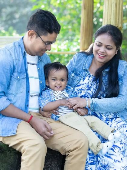 A happy family of three, dressed in coordinating denim, shares a sweet moment on a park bench. The genuine smiles show their close bond.