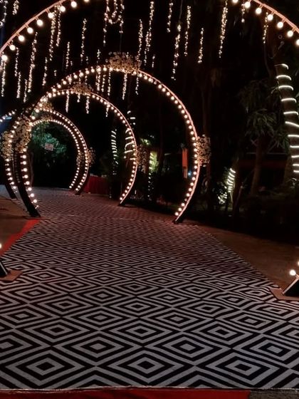 A stunning illuminated walkway for a resort wedding in Panvel. The series of lit arches over a patterned carpet creates a dramatic and glamorous entrance for an evening event.