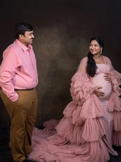 A sweet and simple couple's portrait. The contrast between his casual attire and her dramatic pink gown creates a visually interesting and modern look for their maternity shoot.