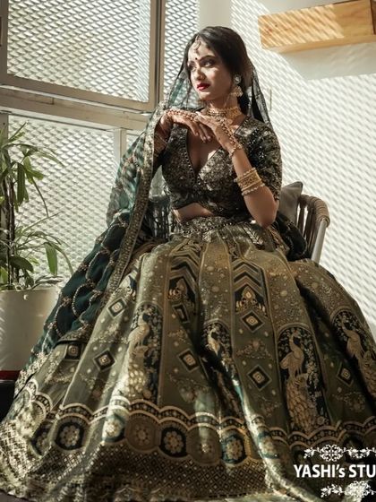A seated portrait of a model in a designer bridal lehenga, showcasing its volume and intricate details.