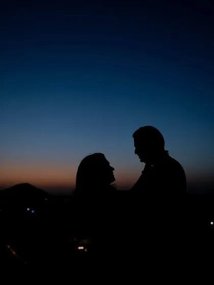 A silhouette of the couple against the twilight sky. This romantic and timeless photo captures a quiet moment of connection during their grand anniversary celebration.