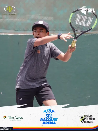 A young boy in a grey shirt and black cap executes a forehand with solid form, a result of consistent training and on-court experience.