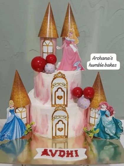 A beautiful princess castle cake featuring Cinderella, Ariel, and Aurora. The golden turrets and elegant details make it a fairytale dream come true.