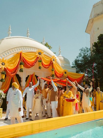A wide shot of a Haldi ceremony, showing the beautiful yellow and orange decor and the lively participation of family and friends.