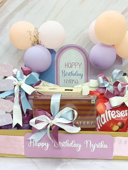 A unique birthday hamper showing how each item is handpicked for the recipient. This one includes custom sweatshirts, their favorite snacks, and a memory box, all in a pastel-themed crate.