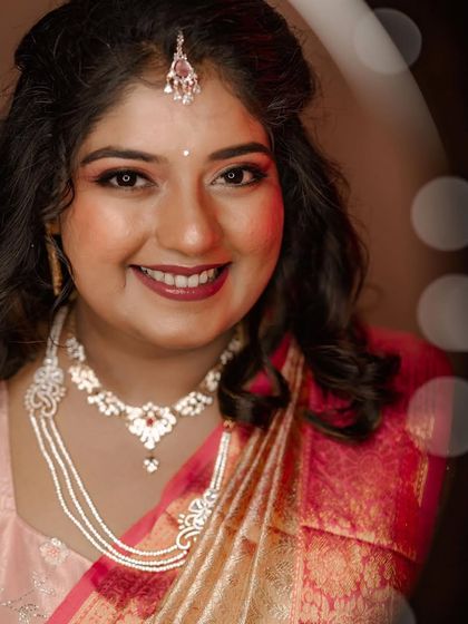 A happy bride in a pink and gold saree, her portrait enhanced with a soft bokeh effect for a dreamy feel.
