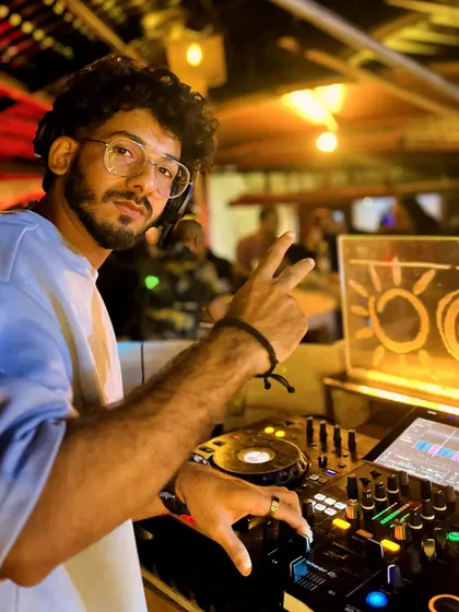 A close-up shot of me at the console at Cafe Mambo, giving a peace sign. I bring a confident and relaxed vibe to my performances.