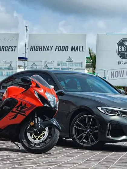 A powerful duo, a Suzuki Hayabusa superbike and a BMW sedan, parked side-by-side, representing the blend of two-wheel and four-wheel enthusiasts who visit us.