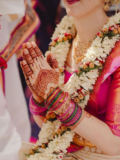 A close-up of Elisabetta's hands in a gesture of prayer during her wedding ceremony. The intricate henna and colorful bangles beautifully represent her embrace of Indian culture.