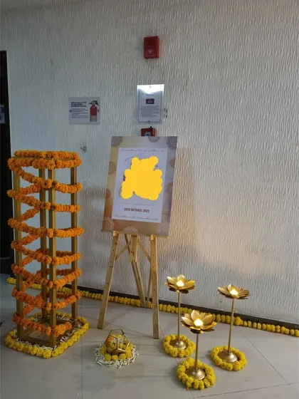 The entrance to a home Mehendi, decorated with marigold garlands and traditional lotus-shaped candle holders. A simple easel with a welcome sign completes the warm and inviting setup.