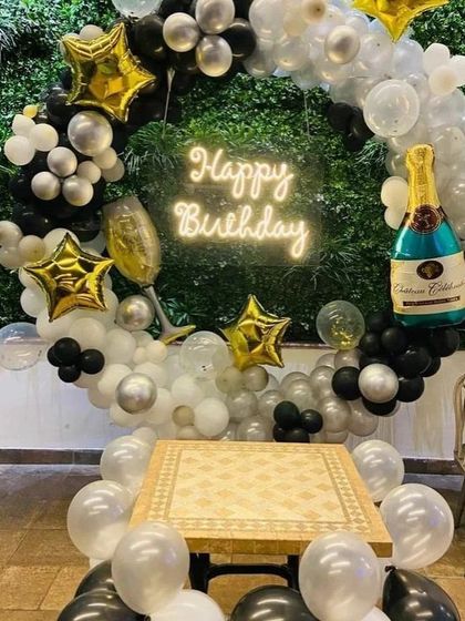 This birthday backdrop is all about celebration. It includes a balloon ring with star and champagne bottle foil balloons, all centered around a "Happy Birthday" neon sign, creating a fun and festive corner for photos.