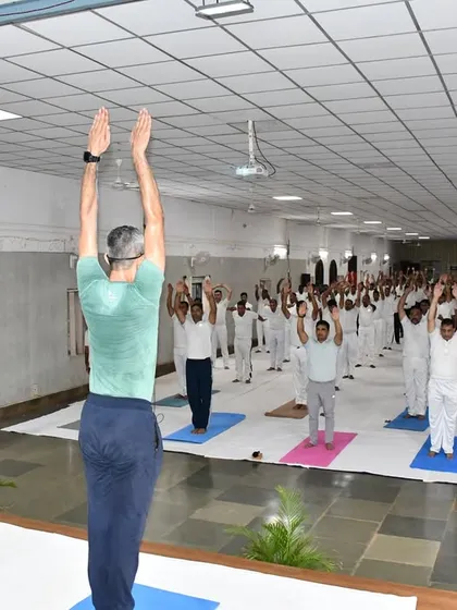 An instructor leading the army camp in a standing asana. The focus is on correct alignment and mindful movement to maximize benefits and prevent injury.