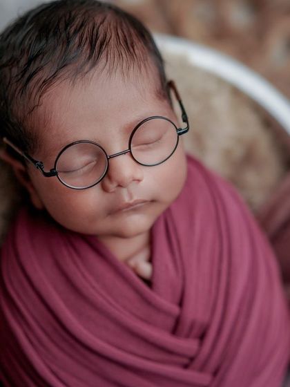 Dreaming of grand adventures. This peaceful, swaddled pose is made even more special with the addition of the cute, round glasses.