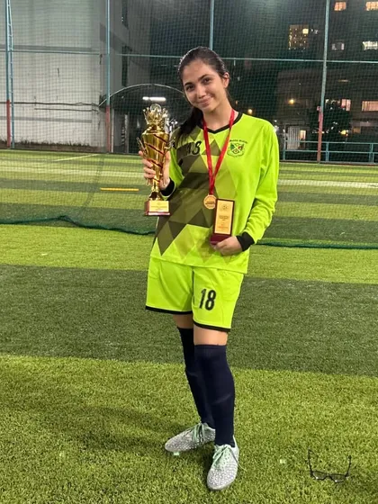 Our goalkeeper, a key part of our U17 championship-winning team, proudly holds her trophy and medal. We train every position to excel.