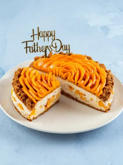 A slice of our Mango Biscoff Cheesecake, a perfect treat for Father's Day. The creamy mango cheesecake and crunchy crust are a winning combination.