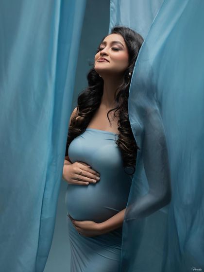 The gentle folds of the blue fabric create a cocoon-like effect, symbolizing the safe and loving world you are creating for your little one.