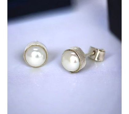 Classic pearl studs with a textured silver bezel setting, adding a touch of rustic charm to a timeless piece.
