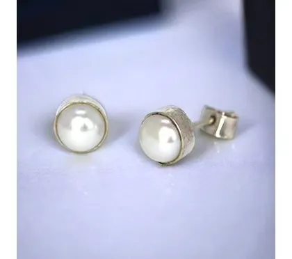Classic pearl studs with a textured silver bezel setting, adding a touch of rustic charm to a timeless piece.