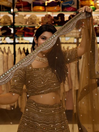 A playful peek from behind the dupatta of this mehendi-green lehenga, showing off the beautiful mirror work border.