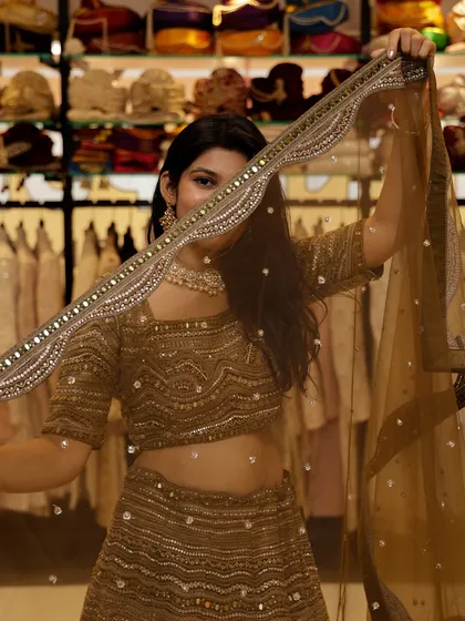 A playful peek from behind the dupatta of this mehendi-green lehenga, showing off the beautiful mirror work border.