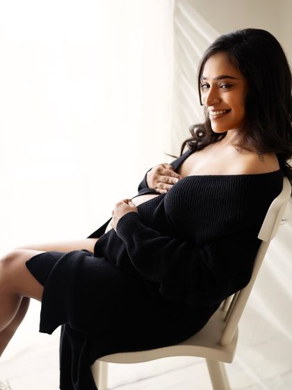 A cozy and intimate seated portrait. The soft knit cardigan adds a layer of texture and comfort, showing a different, more relaxed side of a glam session.