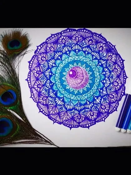 A detailed mandala created with shades of blue and purple, symbolizing tranquility and spirituality. I've used fine-tipped markers to create layers of intricate patterns, with a central gem-like motif, all designed to create a sense of calm and focus.