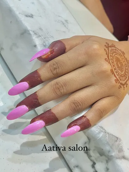 A popular combination for festive seasons is pairing mehendi with fresh nail art. This image shows a simple mandala mehendi on the back of the hand, perfectly complemented by long, bright pink stiletto nail extensions.