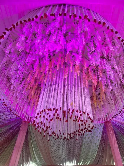 A close-up of one of my signature floral chandeliers. I use a combination of hanging flower strings and fabric strips, illuminated with colored lights to match the event's theme.