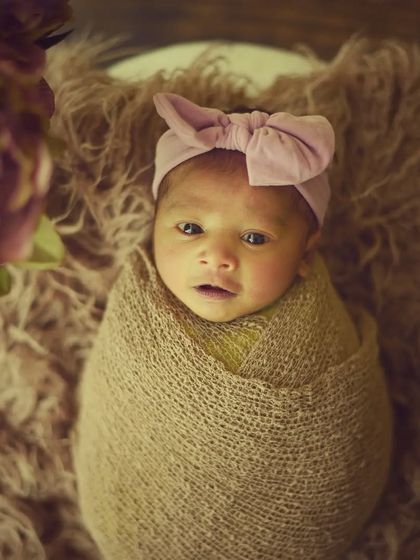 A precious awake moment. This little doll is looking right at the camera, beautifully wrapped and wearing a sweet pink bow headband.