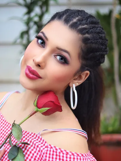 A beauty shot with a braided hairstyle and a red rose. The focus on the flawless makeup and expressive look is ideal for cosmetic brands and makeup artist portfolios.